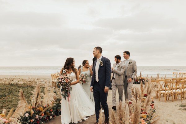 Bride and groom bridesmaids and groomsmen pose for a picture beach setting they walk