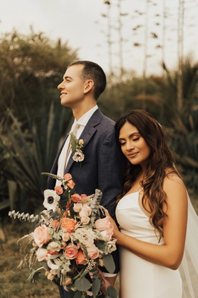 Bride and groom standing on grass walking in front of palm trees beach setting