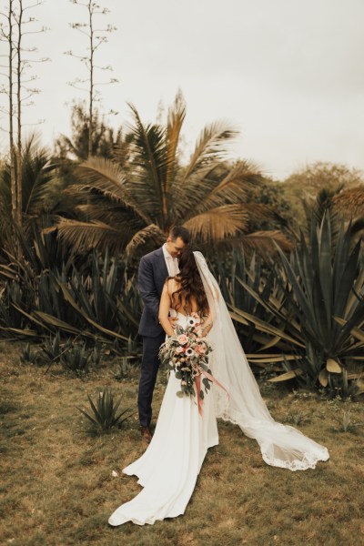 Bride and groom go in for a kiss palm trees in background