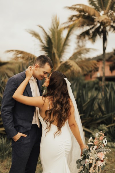 Bride and groom go in for a kiss palm trees in background