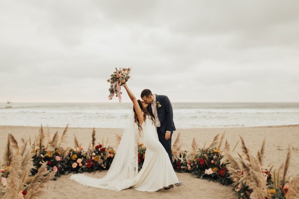 Bride and groom bouquet in the air they kiss in front of ocean sea view