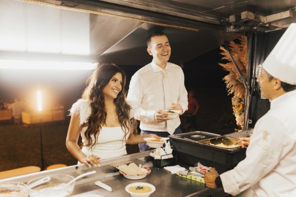 Bride and groom in kitchen setting with food and chef