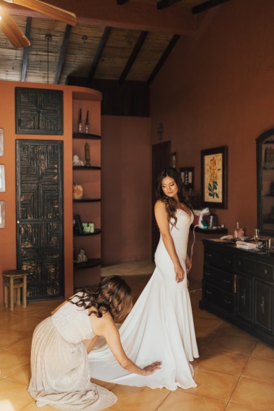 Bride gets help from bridesmaids getting ready