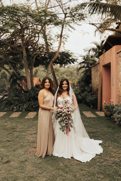 Bridesmaid and bride pose for a photo in garden