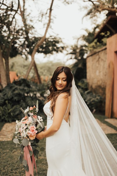 Bride from the site veil detail in garden looks over her shoulder