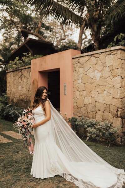 Bride standing in garden holding bouquet over the shoulder