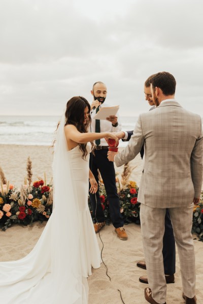 Bride groom and celebrant at alter reading speech on beach setting