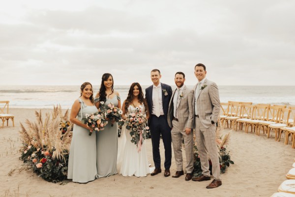 Bride and groom bridesmaids and groomsmen pose for a picture beach setting