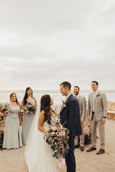 Bride and groom bridesmaids and groomsmen pose for a picture beach setting