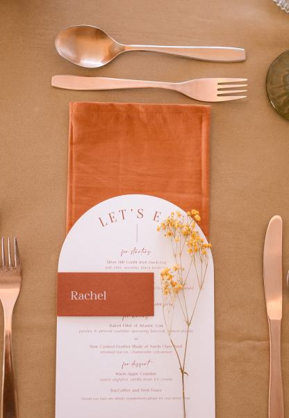 Table setting cutlery orange plates gold spoon flowers and lights menu