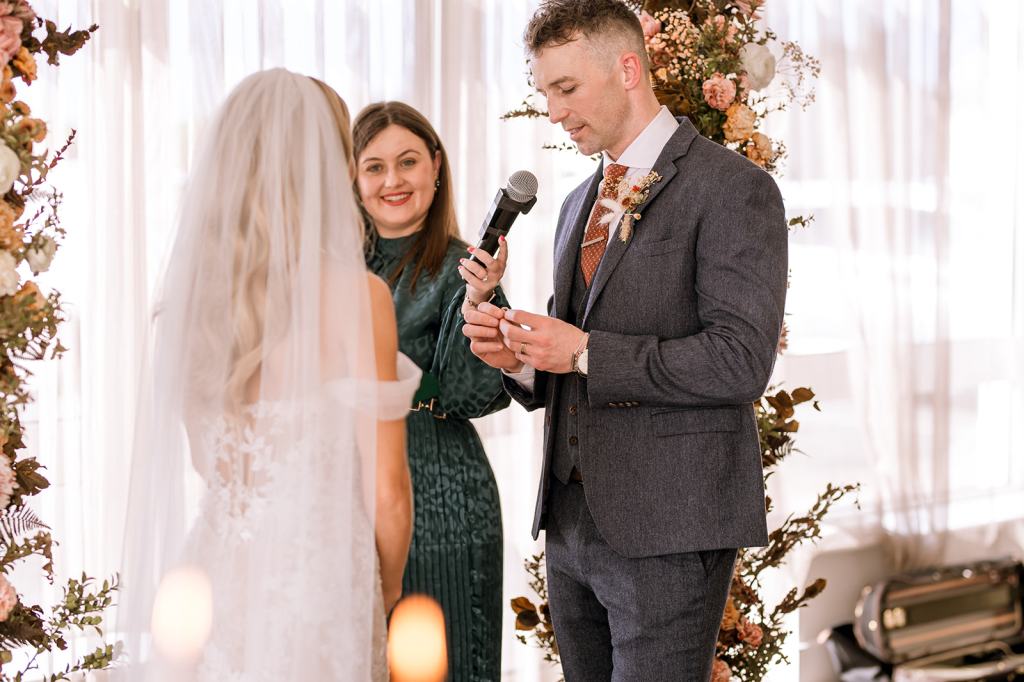 Bride groom and celebrant at alter speaking into microphone