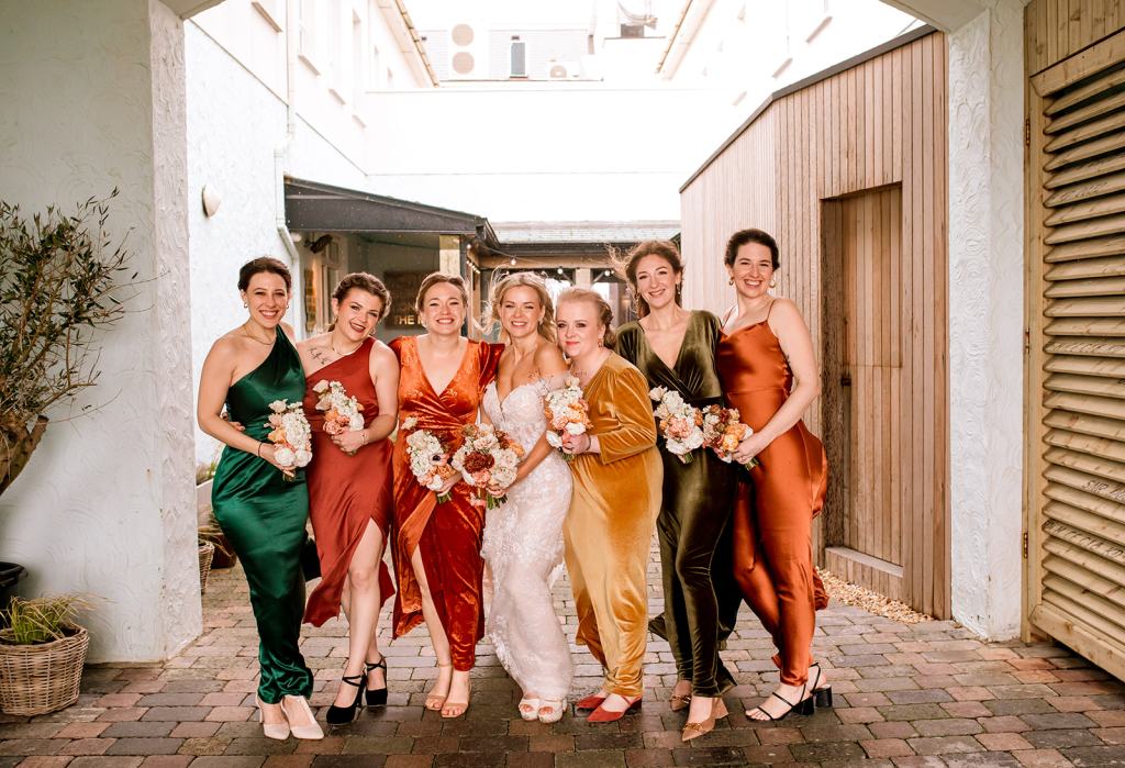 Bride bridesmaids and friends pose for a photo holding bouquet