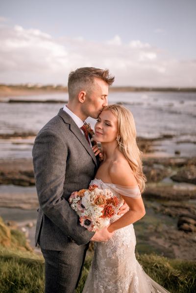 Bride and groom pose in front of beach ocean sea view setting