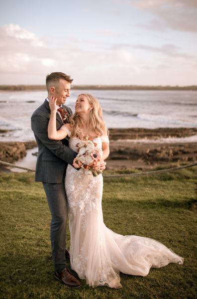 Shot of bride in front of groom placing hand on face bouquet in shot