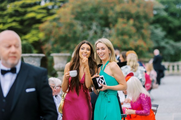 Women wearing blue dress and pink dress smile and laugh