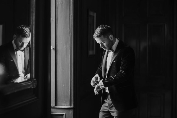 Black and white image of groom getting ready