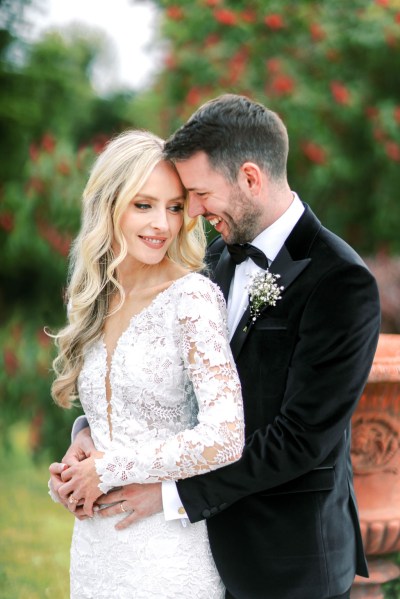 groom has arms around brides waist they're smiling