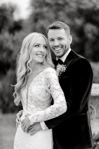 Black and white groom has arms around brides waist