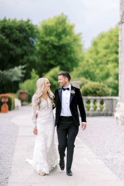 Bride and groom walk in courtyard to wedding venue