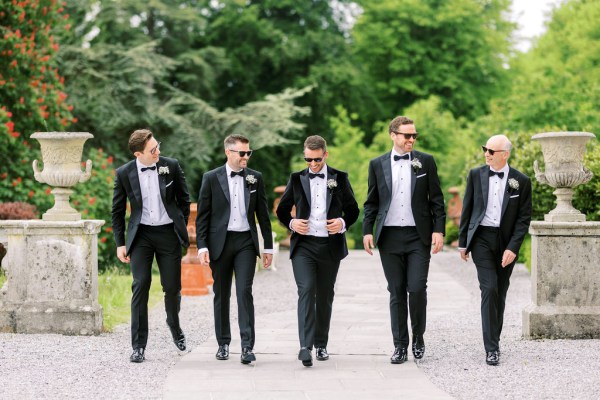 Groom and groomsmen walking down the pathway to garden