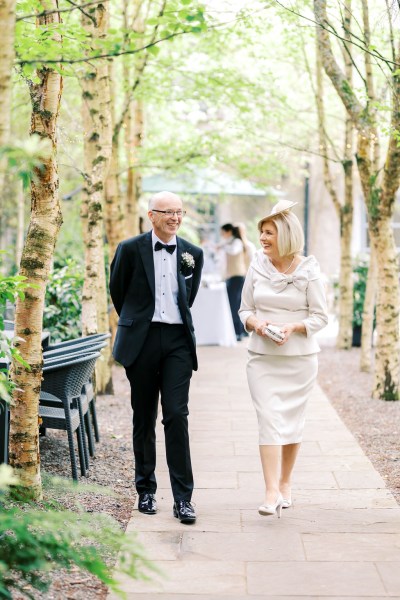 Father and mother walk down pathway to ceremony