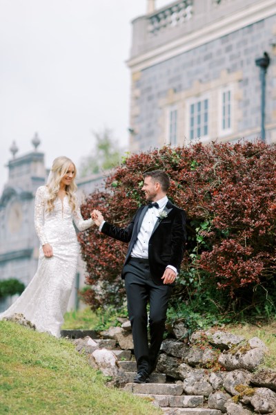 Groom takes brides hands they walk down the steps together