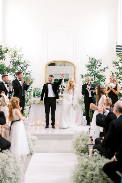 Bride and groom stand at the alter hands in the air