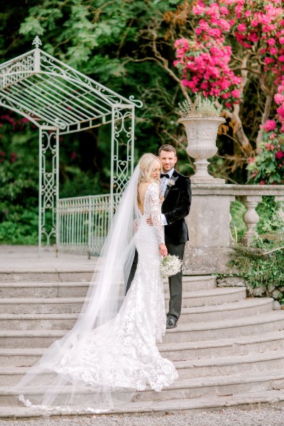 Groom holds bride as they stand on steps