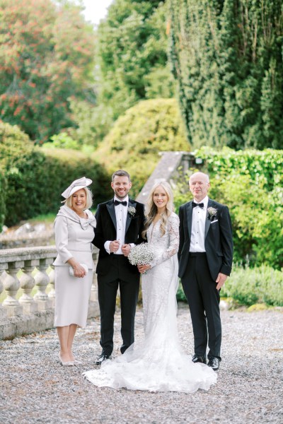 Mother father and bride pose in the garden and groom