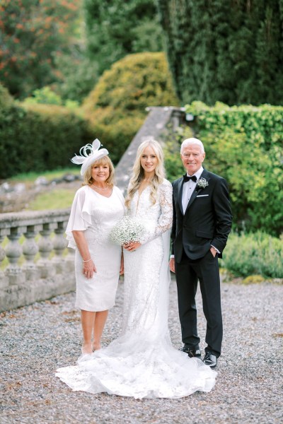 Mother father and bride pose in the garden