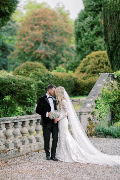 Bride and groom pose together in garden heads touch against each other