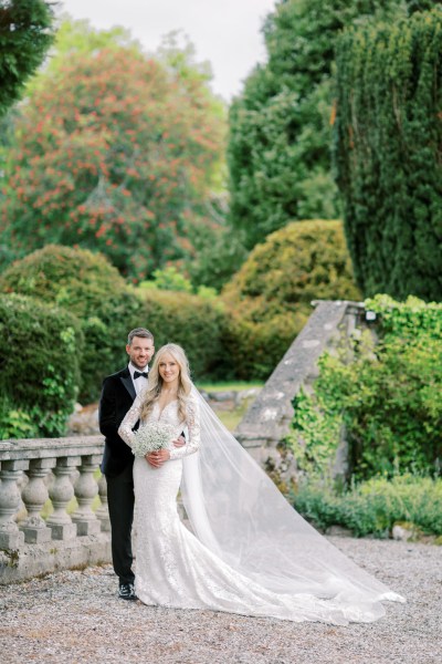 Bride and groom pose together in garden