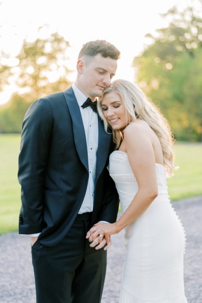 Bride and groom close together grass garden setting