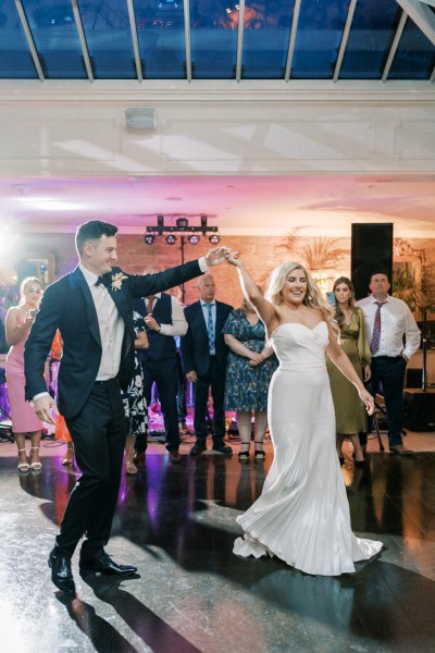 Bride and groom dancing on the dancefloor together guests in background