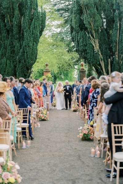 Father of the bride walks down the aisle surrounded by guests