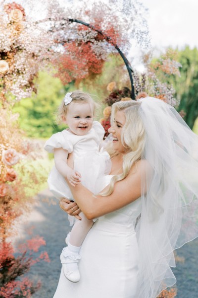 Bride wearing veil holds her little girl daughter