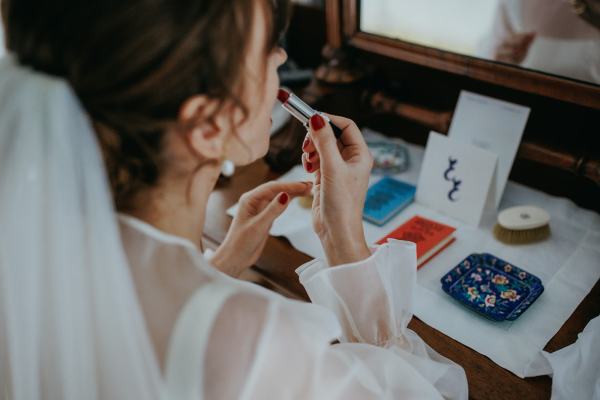 Bride puts on red lipstick in mirror