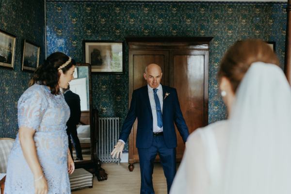 Father sees daughter bride for the first time bridesmaid in shot