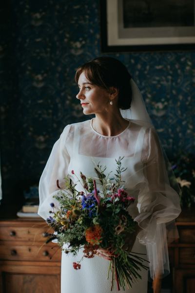 Bride looks to her right holding bouquet in room