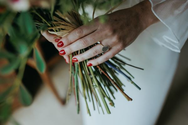 Close up on brides red nails ring and bouquet detail