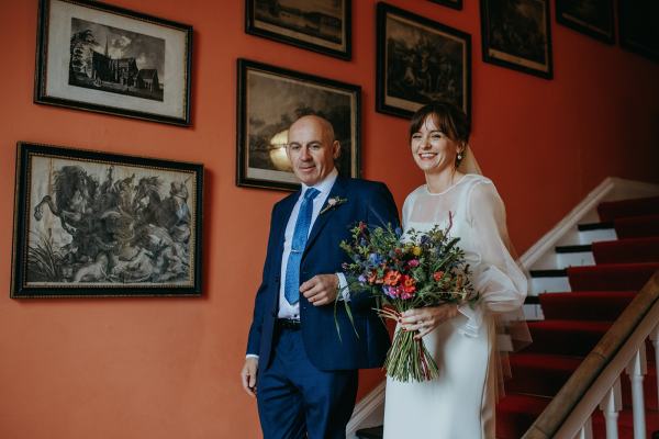 Father of the bride walks daughter down the steps towards ceremony