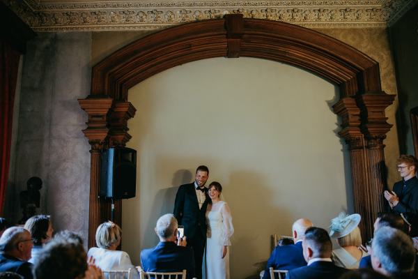 Bride and groom pose and stand at the top of alter setting guests seated