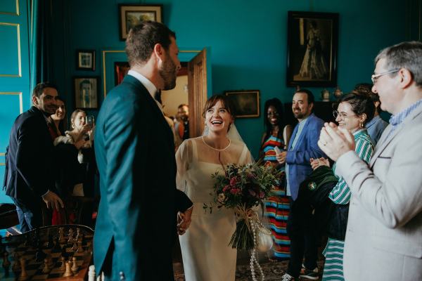 Bride and groom surrounded by guests friends clapping