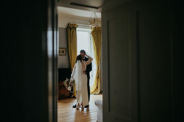 Bride and groom stand and hug in ballroom room setting