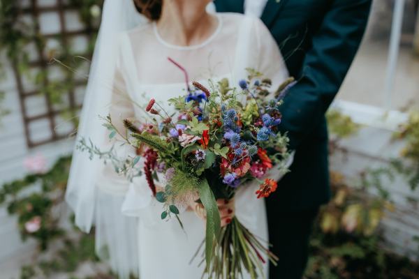 Bride and groom hugging holding each other bouquet in hand