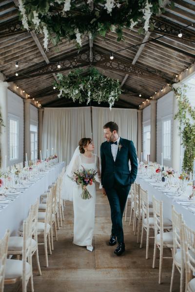 Bride and groom standing in dining room together flower chandelier ahead