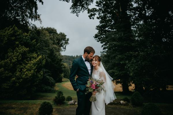 Bride and groom pose in front of landscape together