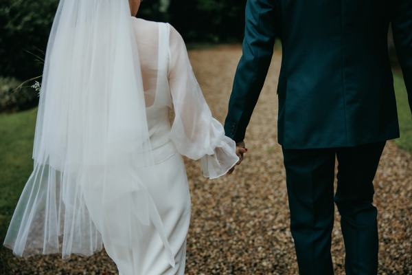 Bride and groom from behind walking hand in hand holding hands