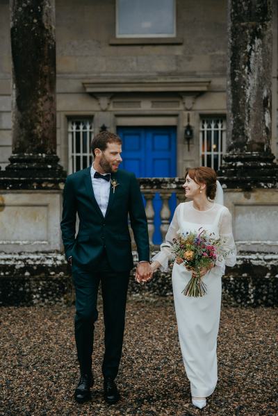 Bride and groom look at each other in courtyard to wedding venue