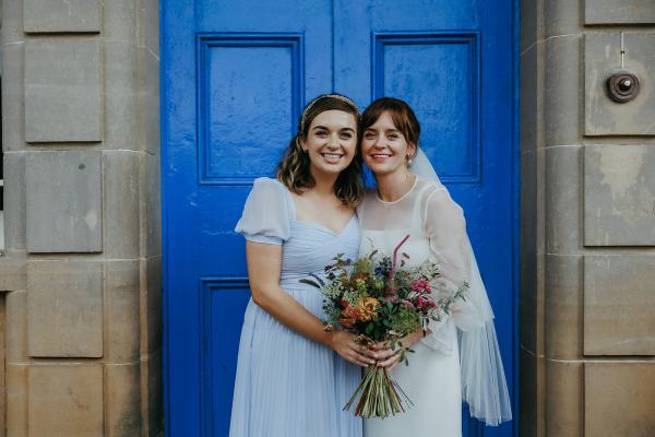 Bride and bridesmaids pose in front of blue door entrance